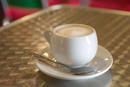 Cup of cappuccino coffee and spoon on a cafe tableの写真素材