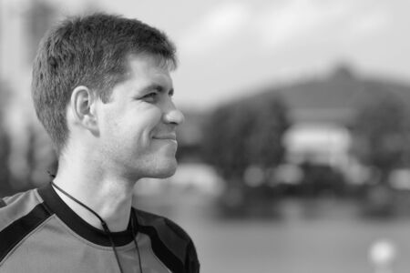 Young smiling sportsman on city view background looking at something in black-and-whiteの写真素材