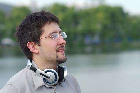 Young smiling man with headphones on city view background looking at somethingの写真素材