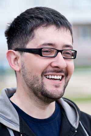 Portrait of a young male caucasian student with beard and glasses smilingの写真素材