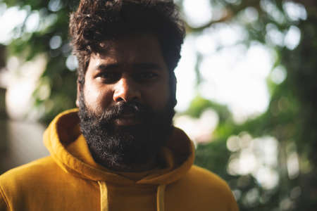 man relaxing in a green public park, Indian male model with green backgroundの写真素材