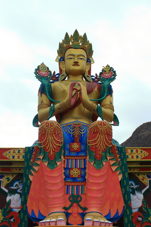 A colorful and decorated Buddha statue in above a Buddhist temple in Diskit village, Nubra Valley, Ladakh, India as seen on a cloudy day.の写真素材