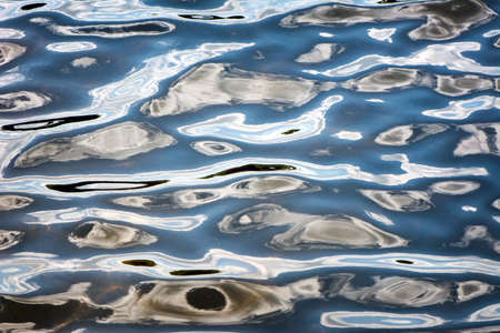 Rippled water reflecting the sky in a flowing pattern.  A great texture image for a background or...