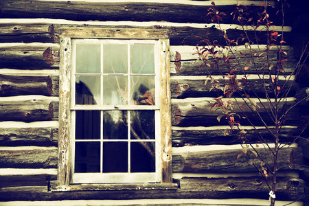 Exterior wall of an old log home featuring a weathered and worn window   Nostalgic processing の写真素材