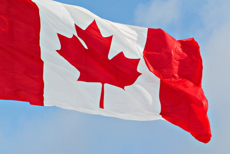 Close up of a Canadian flag flying against a blue sky    