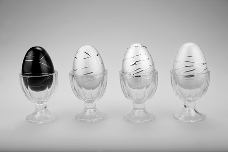 Decorative Easter eggs in cups in a row.  One Black alongside three white on a gray background.  Presented in Black and White.
の写真素材