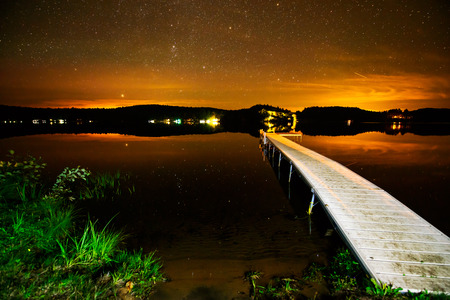 A dock on a lake under a starry sky sunset.の写真素材