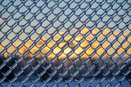 A close up shot of thick layer of ice covering a frozen metal chain link fence after an ice storm.  の写真素材