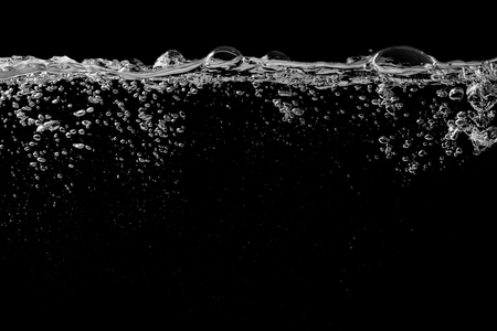 Clear water surface on a black with ripple and bubblesの写真素材