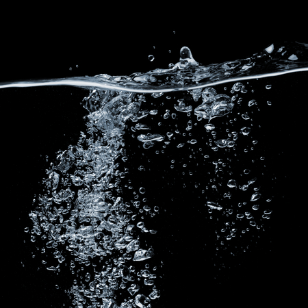 Clear water surface on a black with ripple and bubblesの写真素材