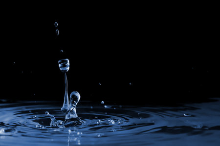 Splash with ripple and drops on the water liquid surface. On a black backgroundの写真素材