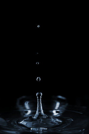 Splash and ripple on the clear water surface liquid from a falling drop. On a dark backgroundの写真素材