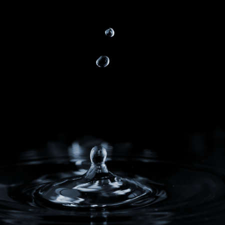 Splash and ripple on the clear water surface liquid from a falling drop. On a dark backgroundの写真素材
