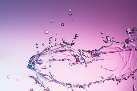 Clear water liquid splash on a purple color backgroundの写真素材