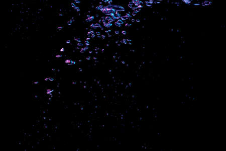 A bubble splash in transparent clear water liquid in red and blue light on a black nature backgroundの写真素材