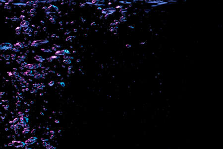 A bubble splash in transparent clear water liquid in red and blue light on a black nature backgroundの写真素材