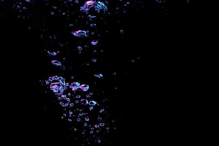 A bubble splash in transparent clear water liquid in red and blue light on a black nature backgroundの写真素材