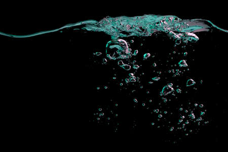 Clear water surface with ripple and bubbles in green and blue light on a black nature backgroundの写真素材
