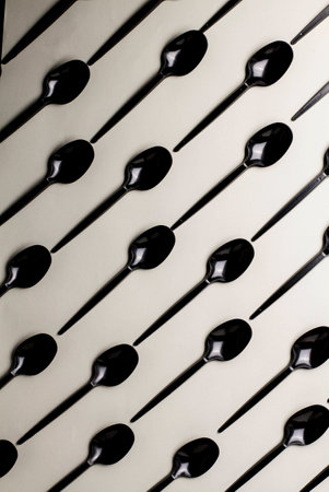 Black plastic spoons on a gray background lie diagonallyの写真素材