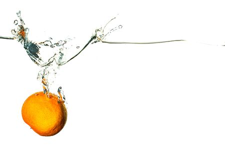 Fresh fruit dives into cold water with bubbles on white backgroundの写真素材