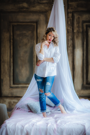 Pretty blonde woman posing on bed with canopyの写真素材