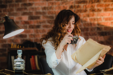 young brunette woman in white shirt quickly doing photo in office the contents of papers and maps on...