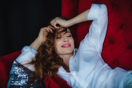 Close up of pretty young woman posing on red sofa and laughingの写真素材