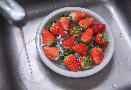 Strawberry fruit falling into the waterの写真素材