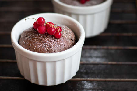 Chocolate fondant in the white ramekin with red currant on the dark background. Lava cake.の写真素材