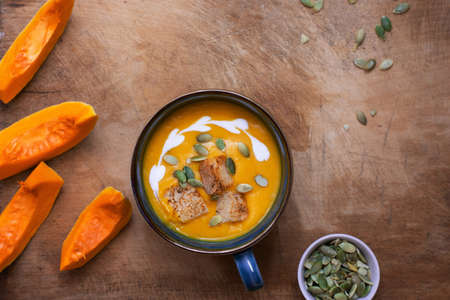 Pumpkin and carrot soup with cream on wooden background. Copy space. Top view.の写真素材