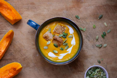 Pumpkin and carrot soup with cream on wooden background. Soup serving.の写真素材