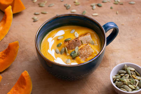 Pumpkin and carrot soup with cream on wooden background. Soup serving.の写真素材