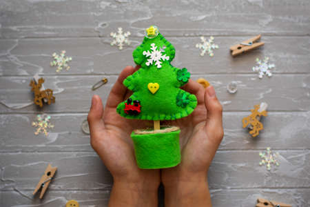 Kid is holding a Christmas tree decoration in his hands. Kid is showing a Christmas tree decoration. Merry Christmas tree project for kids. DIY Christmas tree felt decoration.の写真素材