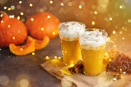Pumpkin spice latte in a glass mug with cinnamon and whipped cream. Bokeh background. Autumn, winter drinks. Holiday drinks. Thanksgiving day.の写真素材
