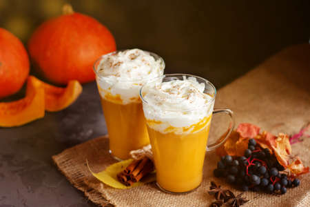 Pumpkin spice latte in a glass mug with cinnamon and whipped cream. Dark background. Autumn, winter drinks. Holiday drinks. Thanksgiving day.の写真素材