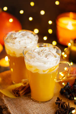 Pumpkin spice latte in a glass mug with cinnamon and whipped cream. Bokeh background. Autumn, winter drinks. Holiday drinks. Christmas drink.の写真素材