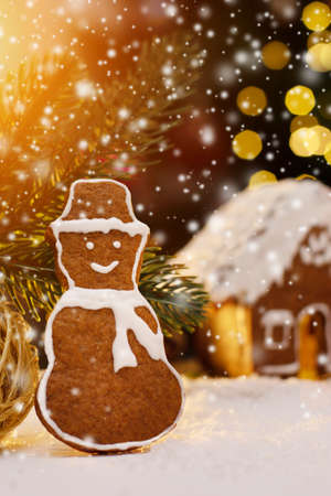 Gingerbread snowman and snow decoration for Christmas and New Year, dark background, selective focus, bokeh. Christmas food. Snowman biscuit.の写真素材