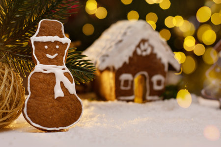 Gingerbread snowman and snow decoration for Christmas and New Year, dark background, selective focus, bokeh. Christmas food. Snowman biscuit. Gingerbread house.の写真素材