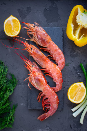 Large langoustines shrimp on a black stone on the black kitchen table. Seafood for a healthy diet. Ingredients. Top view.の写真素材