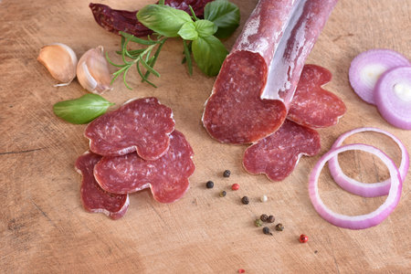 Slices of delicious spanish sausage fuet on the wooden natural kitchen board closeup. Love food concept. Traditional Spanish sausage. Variety of dry cured chorizo. Heart shaped sausage.の写真素材