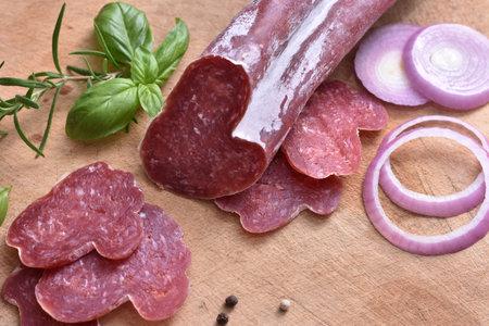 Slices of delicious spanish sausage fuet on the wooden natural kitchen board closeup. Love food concept. Traditional Spanish sausage. Variety of dry cured chorizo. Heart shaped sausage.の写真素材