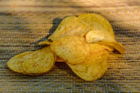 Slices of potato chips on a wooden background. Fried potatoesの写真素材