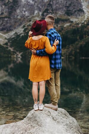Lovely couple travelling together in the mountains, walking around the lake Morskie oko in Tatry. Amazing girl in yellow dress. Stunning view.の写真素材