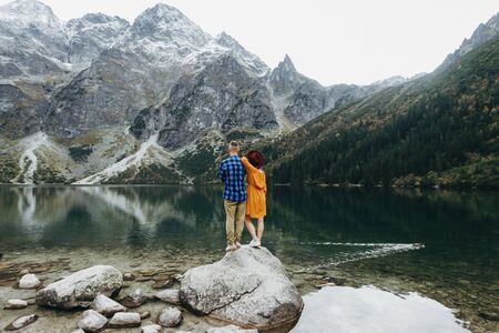 Lovely couple travelling together in the mountains, walking around the lake Morskie oko in Tatry. Amazing girl in yellow dress. Stunning view.の写真素材
