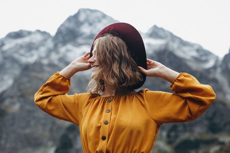 Magnetic girl in the yellow dress and red hat by stunning lake Morskie oko in mountainsの写真素材