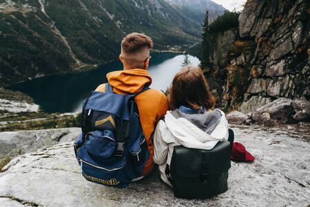 Lovely couple travelling together in the mountains, walking around the lake Morskie oko in Tatry. Amazing girl in a white jacket. Stunning view.の写真素材