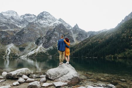 Lovely couple travelling together in the mountains, walking around the lake Morskie oko in Tatry. Amazing girl in yellow dress. Stunning view.の写真素材