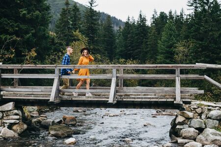 Girl in yellow dress holding boy's hand and running high in the mountains.  Breathtaking view.の写真素材