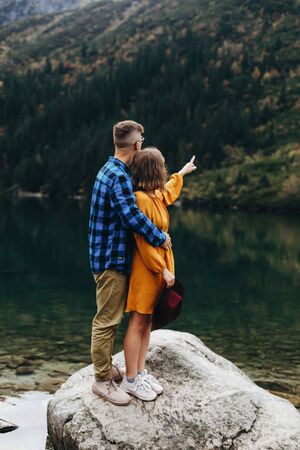 Lovely couple travelling together in the mountains, walking around the lake Morskie oko in Tatry. Amazing girl in yellow dress. Stunning view.の写真素材
