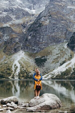 Lovely couple travelling together in the mountains, walking around the lake Morskie oko in Tatry. Amazing girl in yellow dress. Stunning view.の写真素材